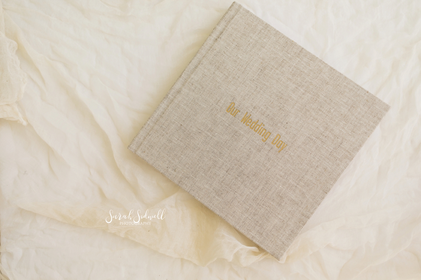 A high quality wedding photo album sits on a table as an example of what the photographers offers to her clients. 