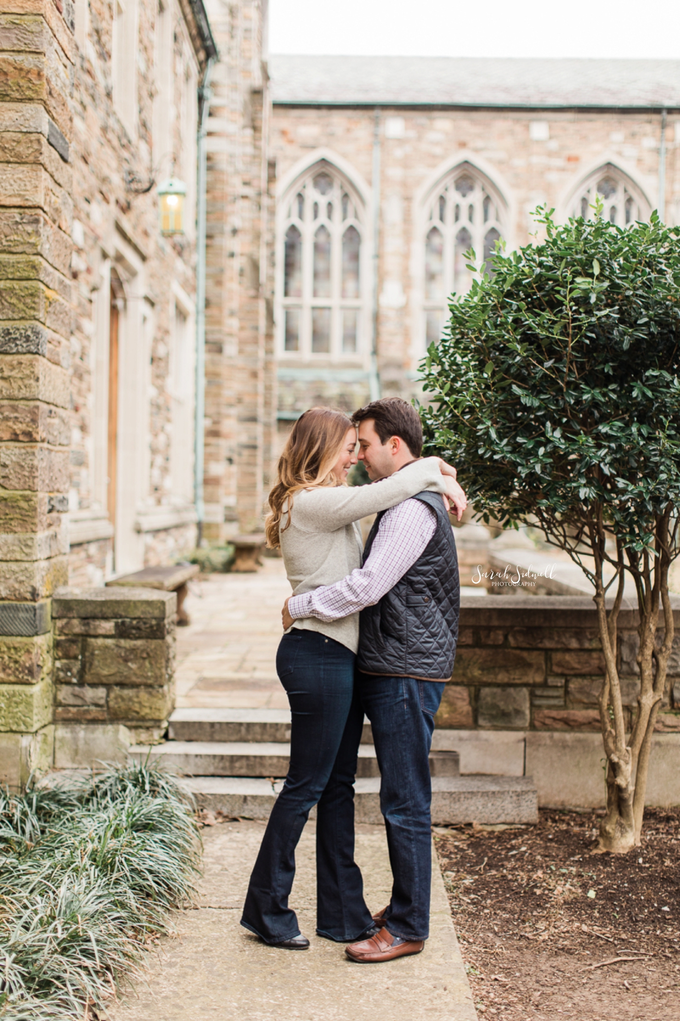 A couple hug in a park in front of the camera of their Nashville Engagement Photographer. 