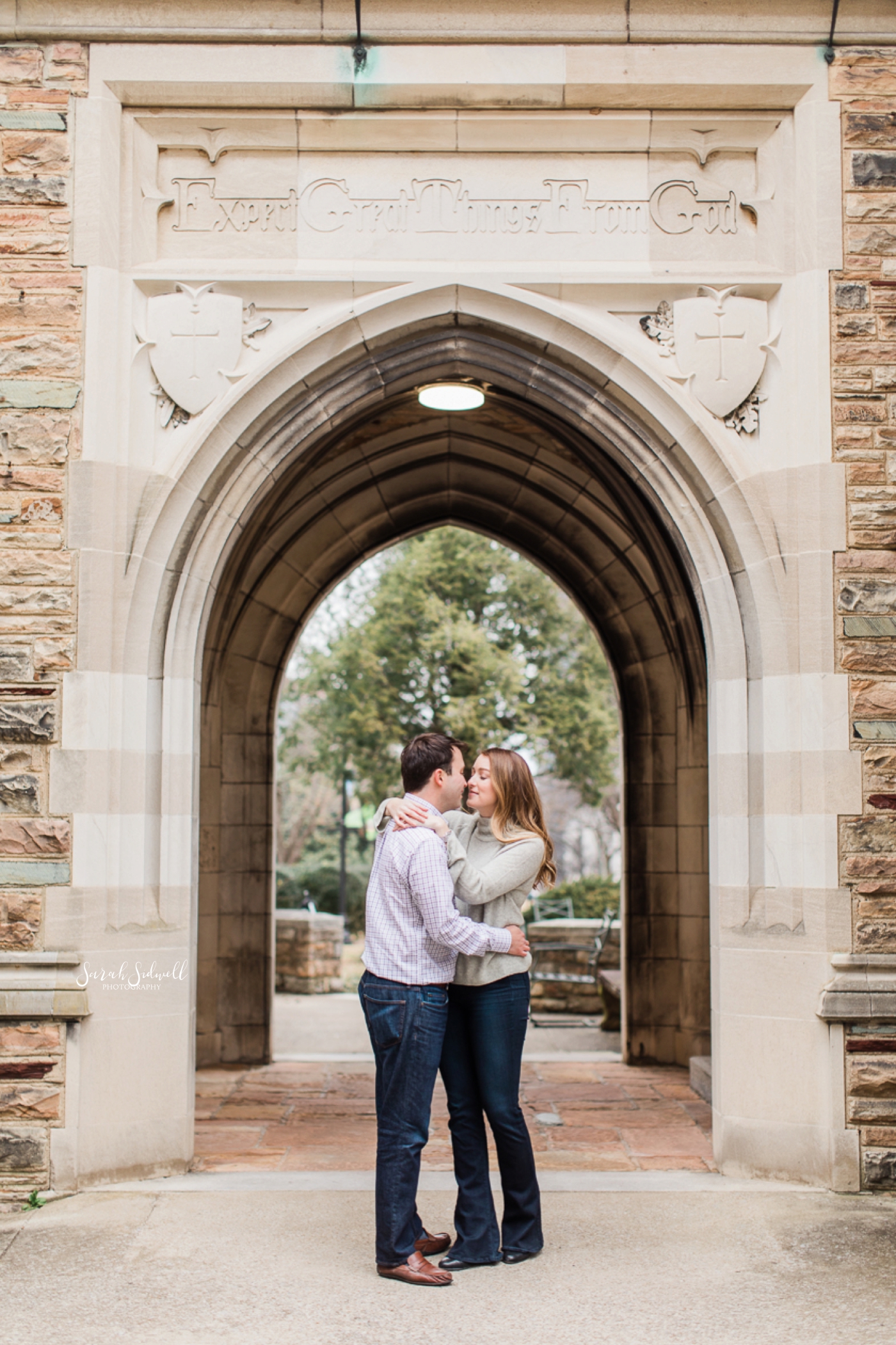 A couple kiss beneath an archway. 