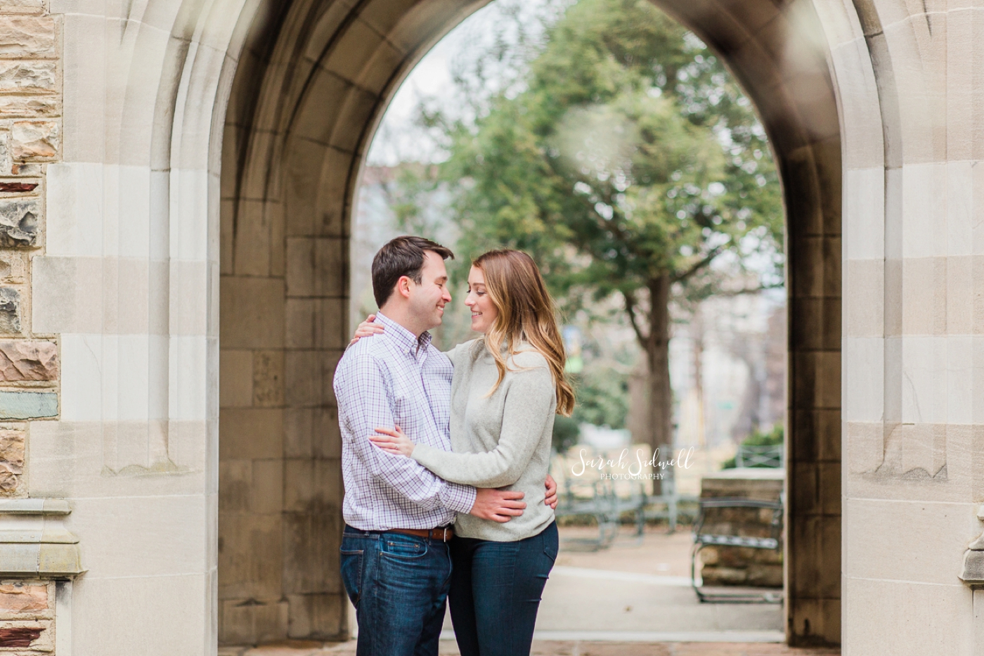 A couple share a close moment under an archway. 