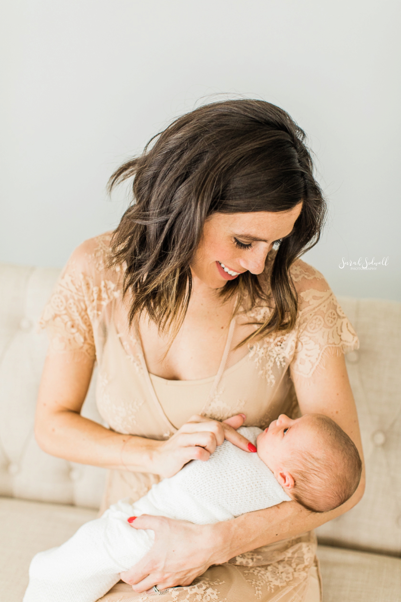 A mother looks down at her baby, captured by a Nashville Newborn Photographer. 