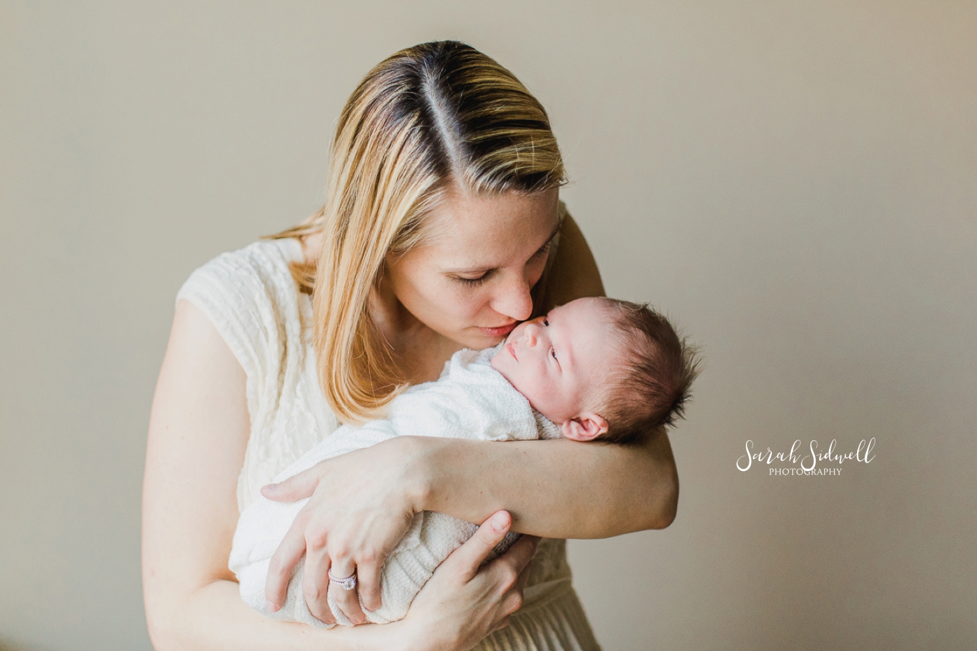 A mother kisses her baby, captured by a newborn photographer Nashville. 