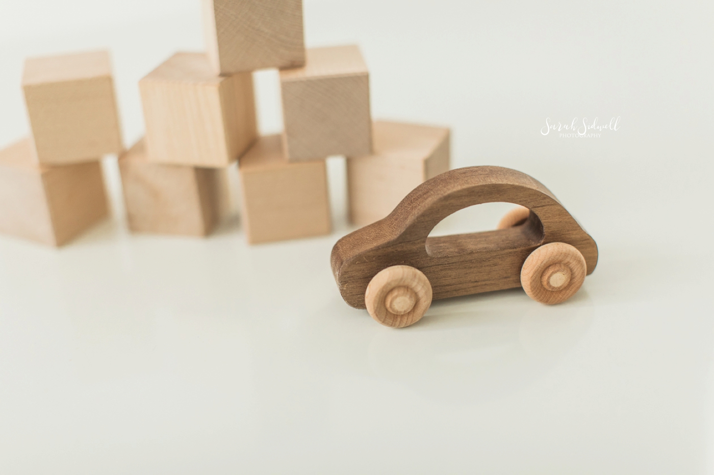 Wooden toys are sitting on a white floor. 