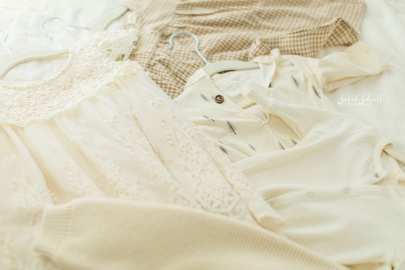 Cream colored clothing is laid out on a floor. 
