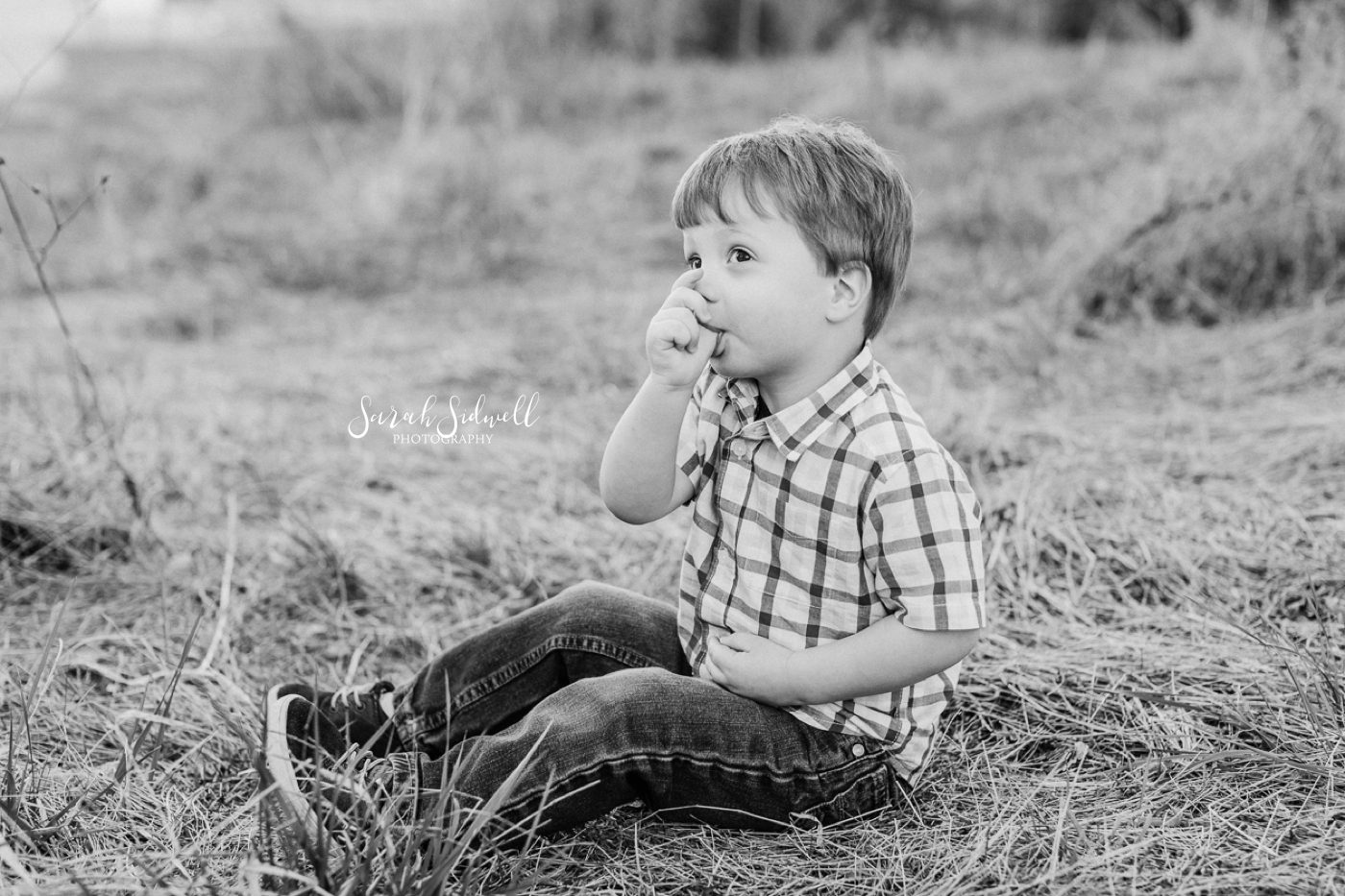 A boy sits in the grass. 
