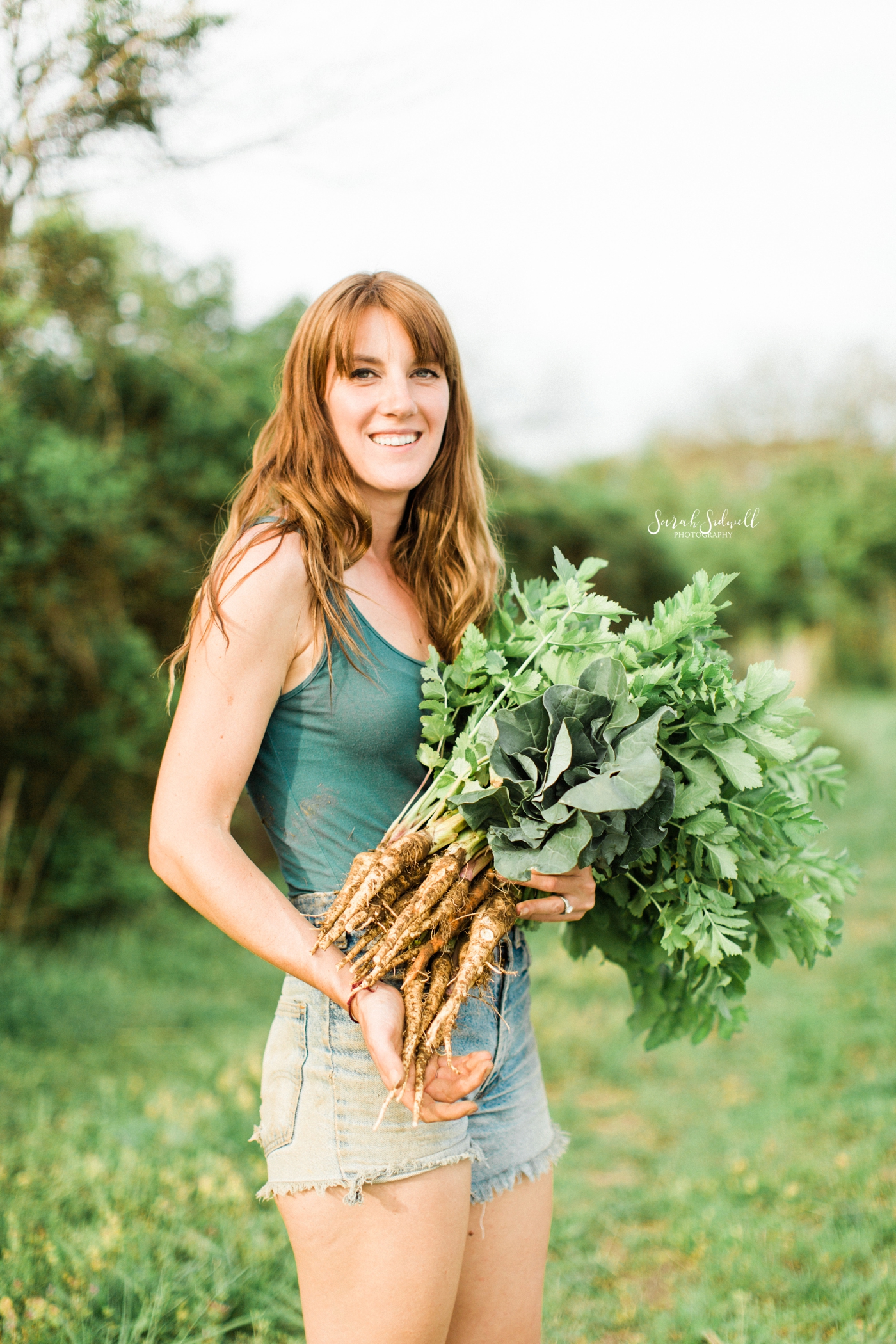 A woman holds a bunch of carrots. 