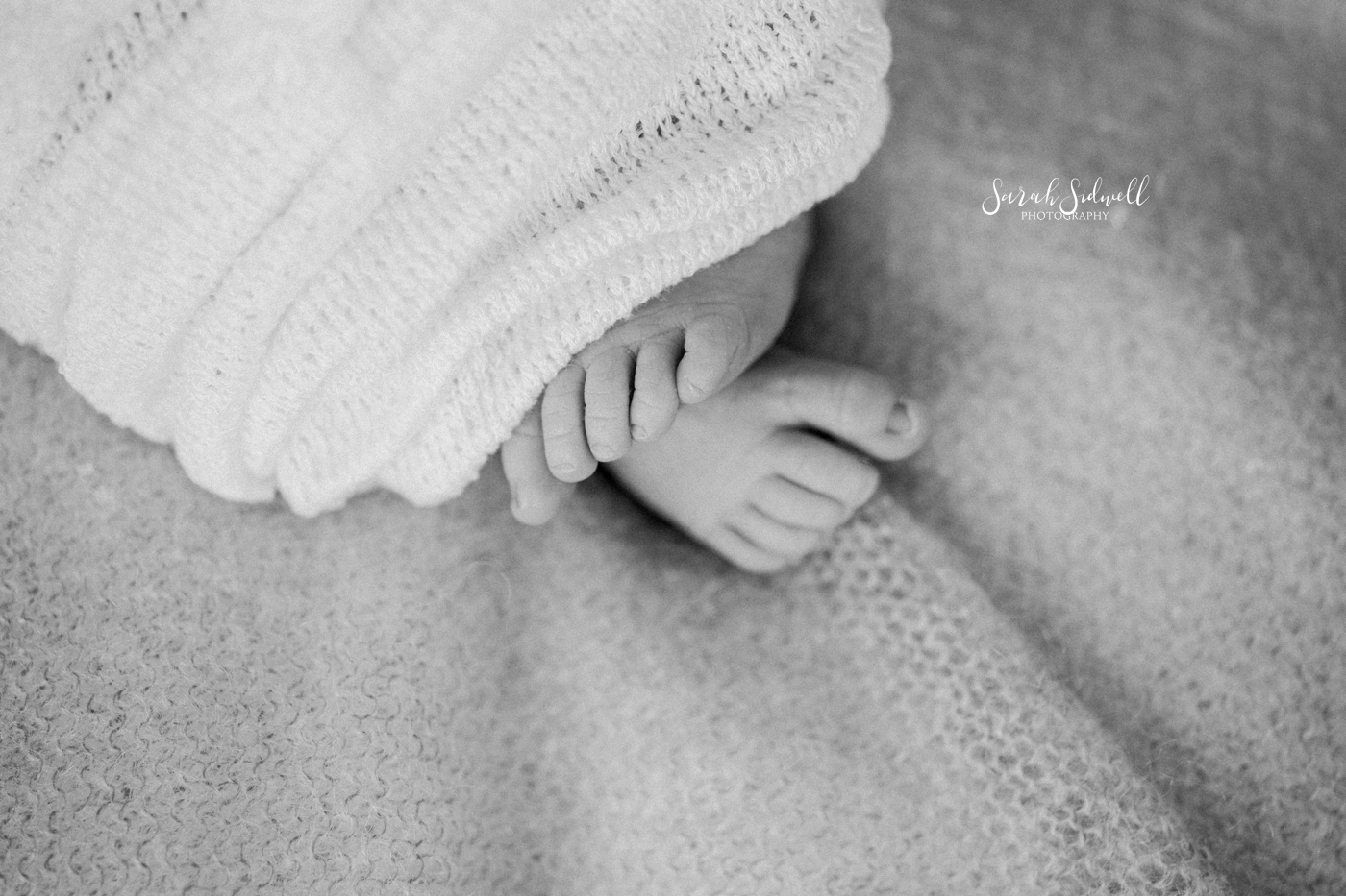 A baby's feet peek out of a blanket. 