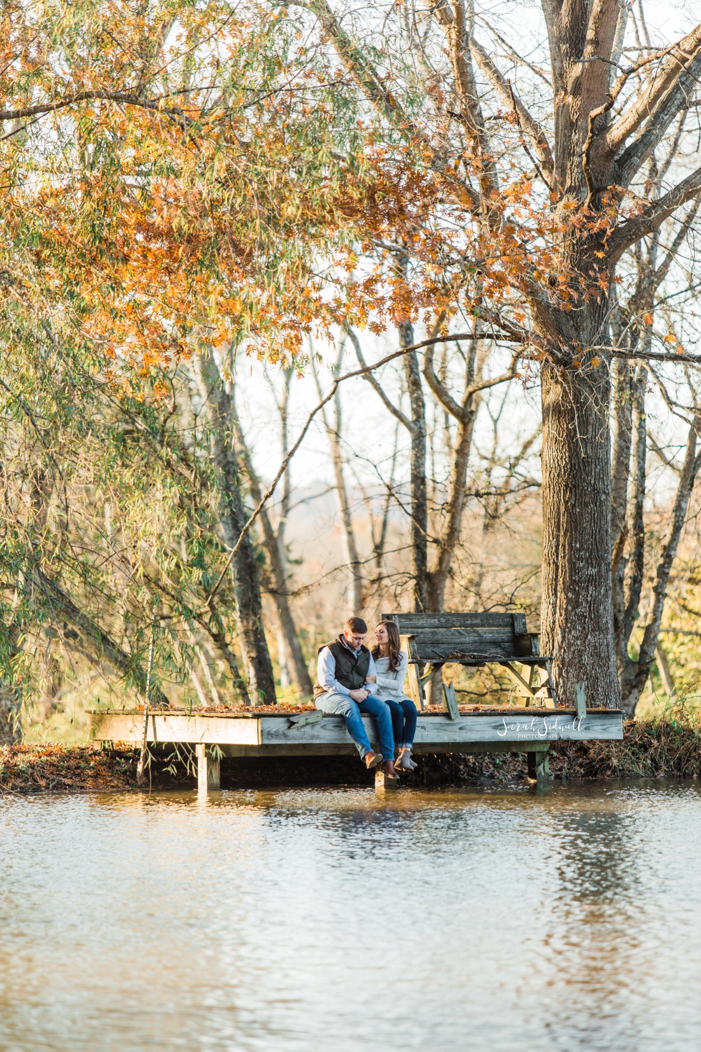 An engaged couple sit on a dock near a lake | Engagement Photography Nashville