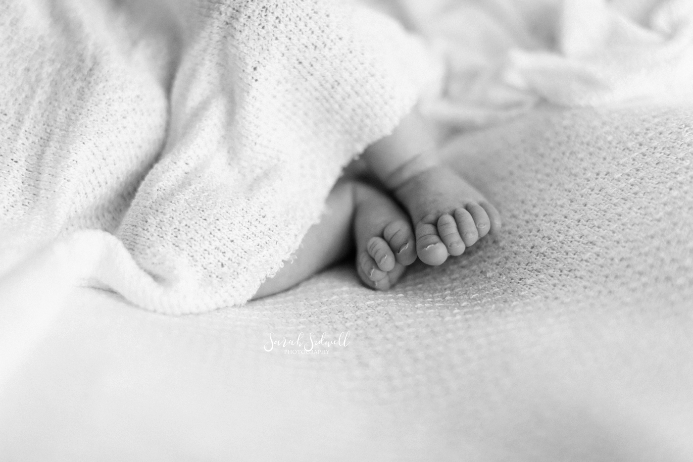 A baby's feet wiggle free from her blanket. 