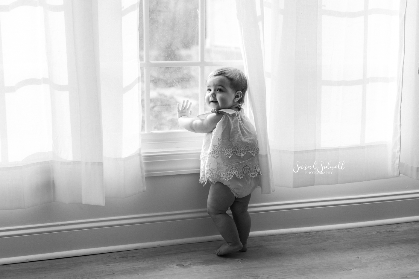 A baby stands by a window | Nashville Baby Photographer 