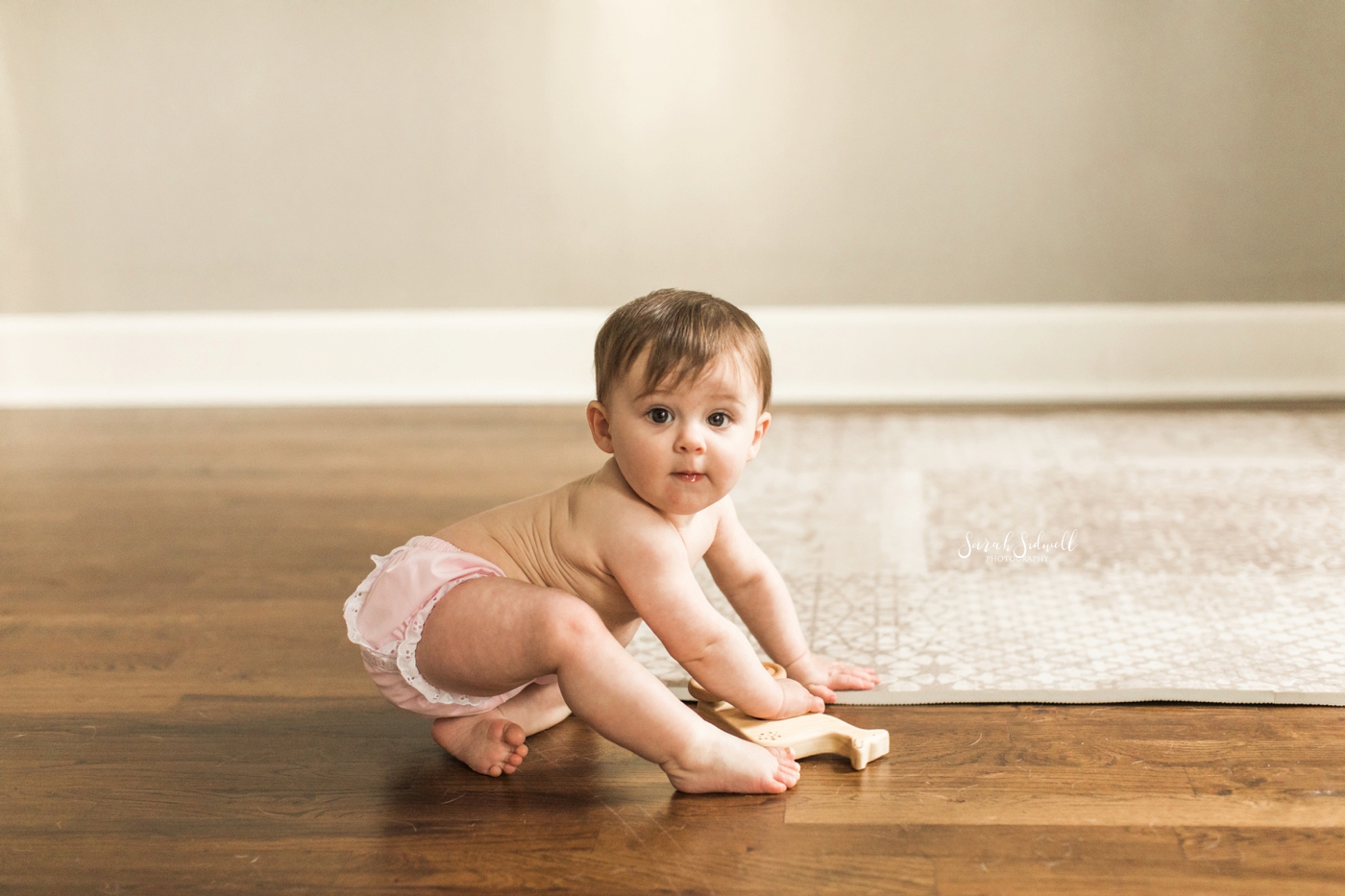A baby crawls on a wood floor | Sitting Baby Session In Nashville