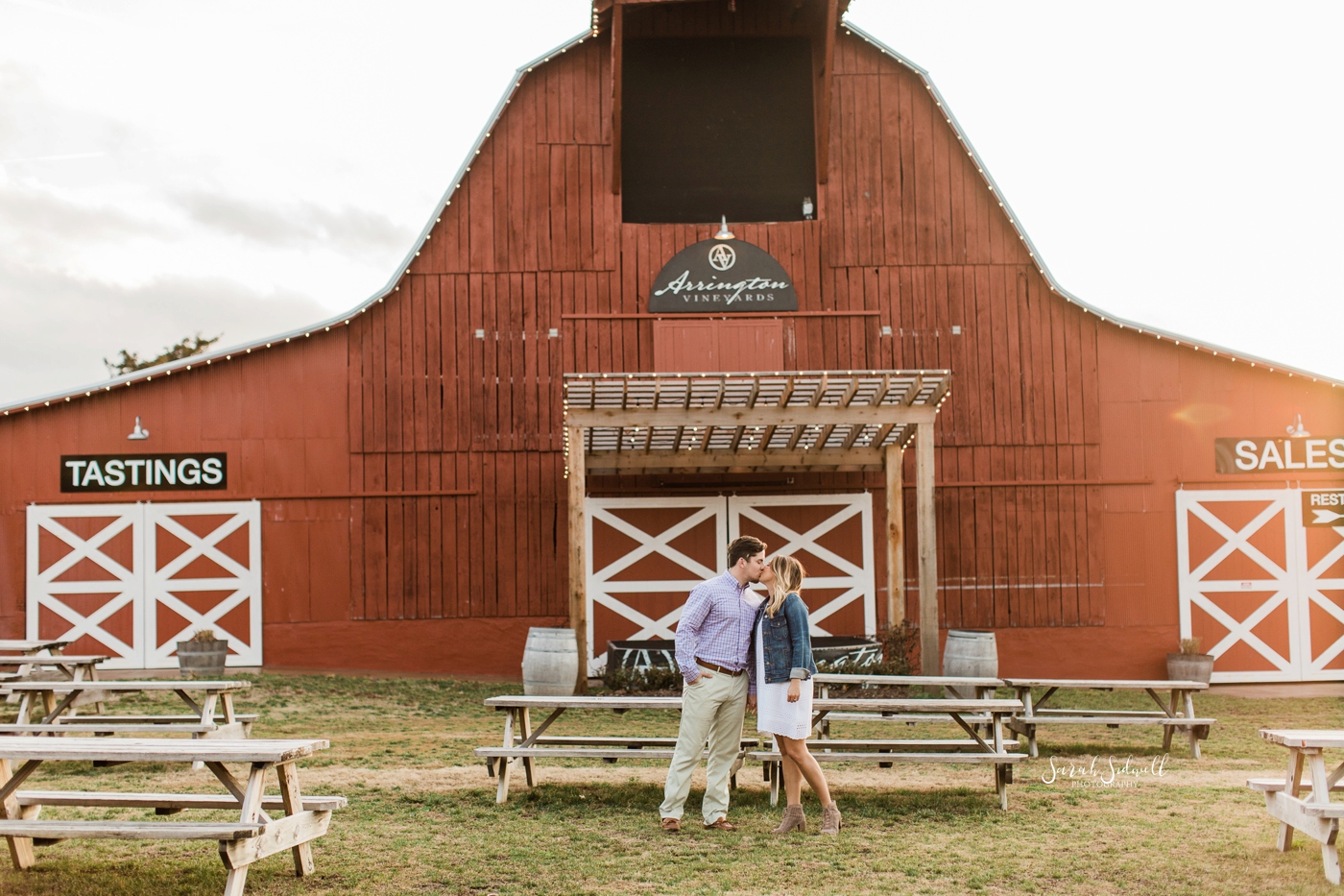 A couple stop to embrace in front of a barn at Arrington Vineyards. 