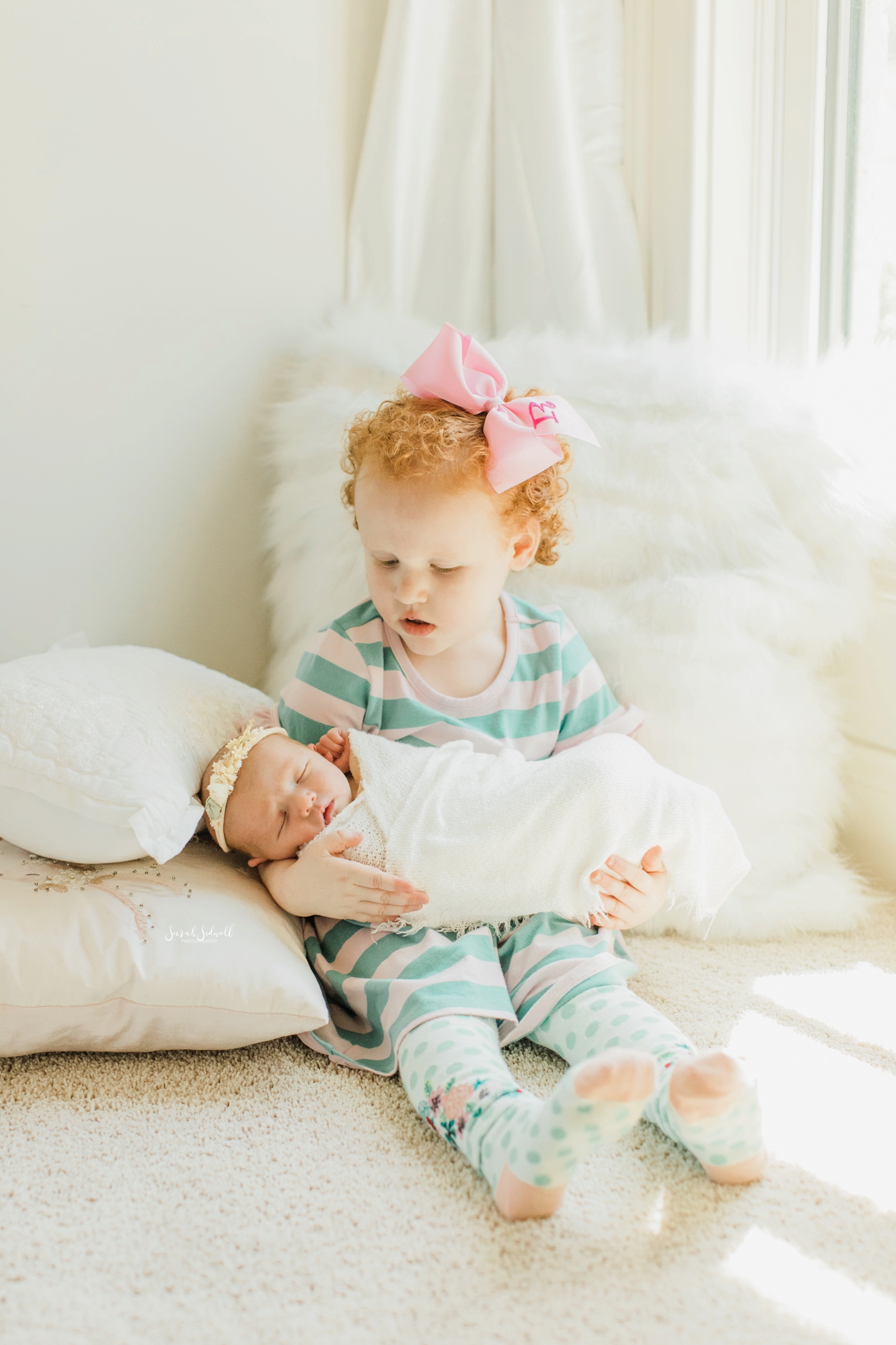 A toddler holds her new baby sister | Home Newborn Session
