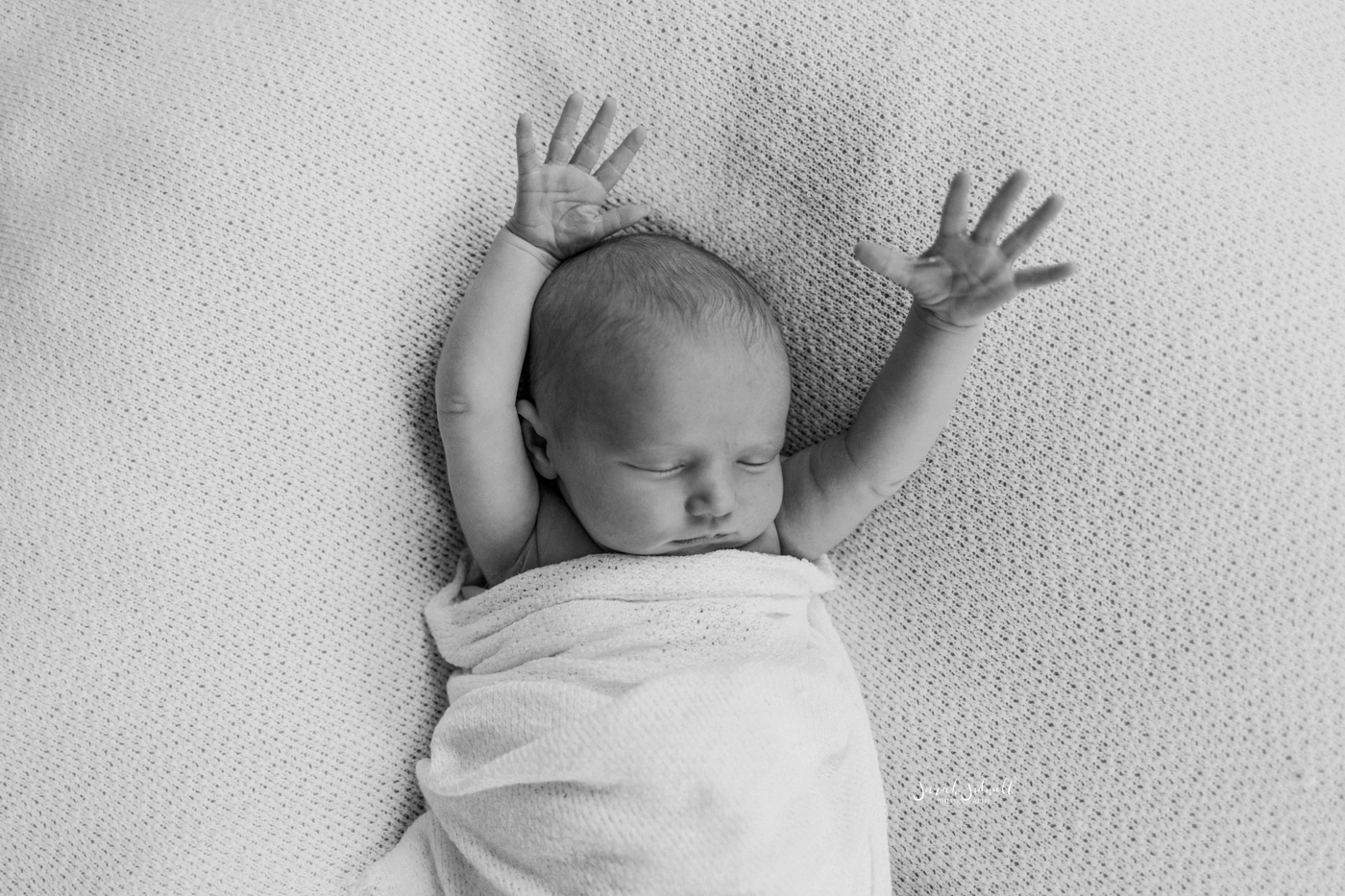 A baby stretches her arms over her head in her sleep. 