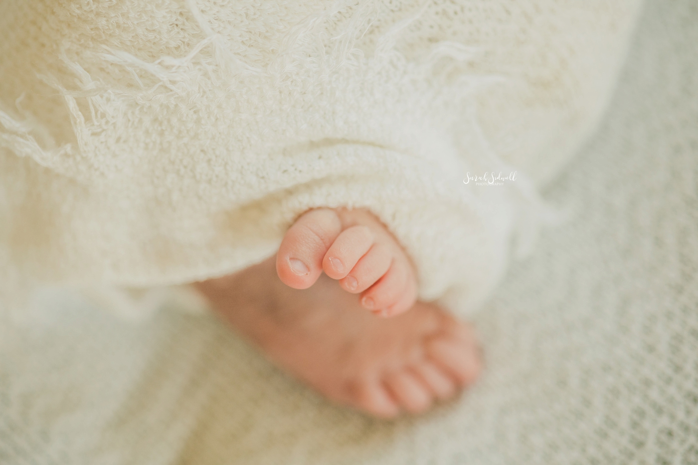 A baby's toes come free from her blanket. 