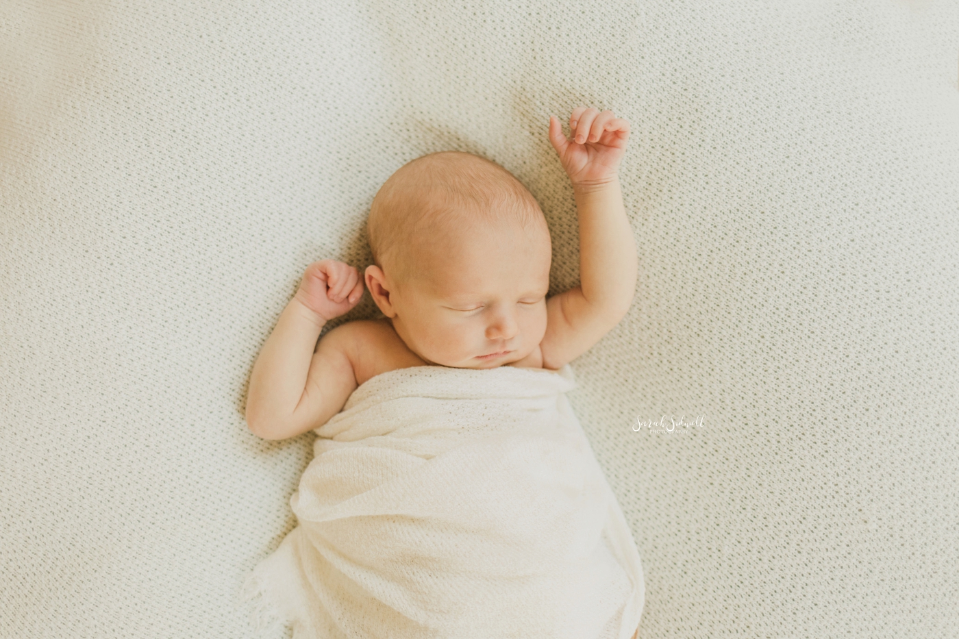 A newborn baby girl stretches her arms in her sleep | Home Newborn Session