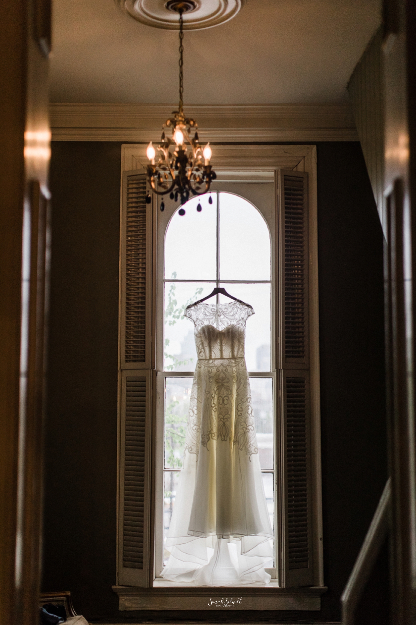 A wedding dress hangs in a window at the East Ivy Mansion. 