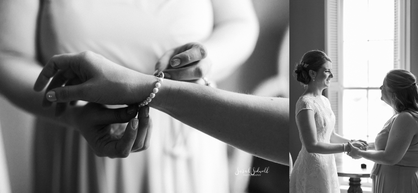 A woman buckles a bracelet onto a bride's wrist. 