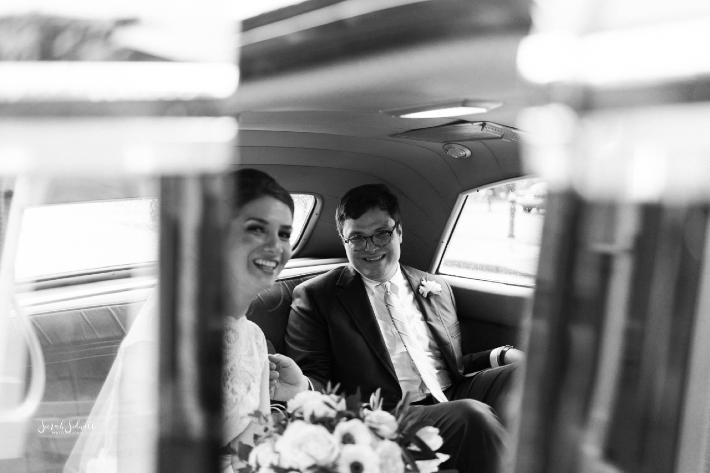 A bride and groom get into their get away car. 