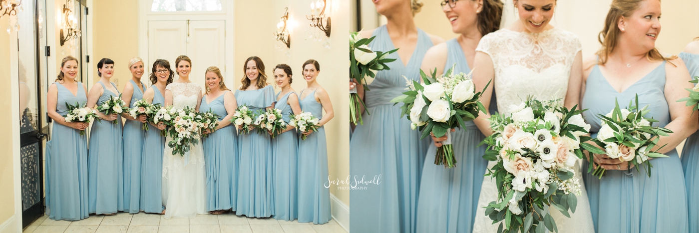 A bride stands with her bridesmaids who wear blue dresses. 