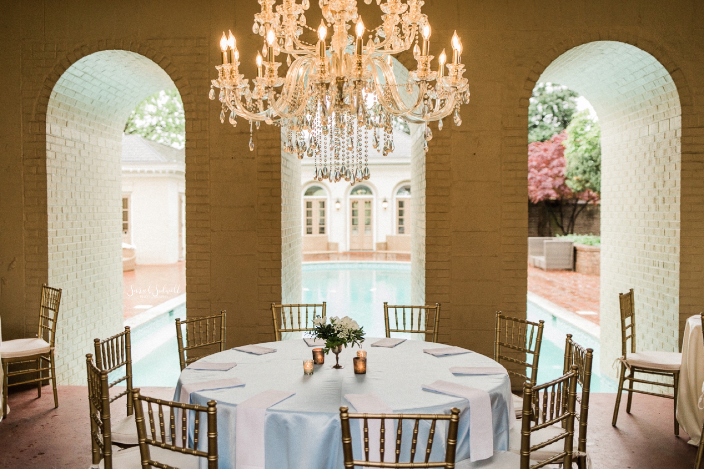 A venue has tables covered in white linen for a wedding reception. 