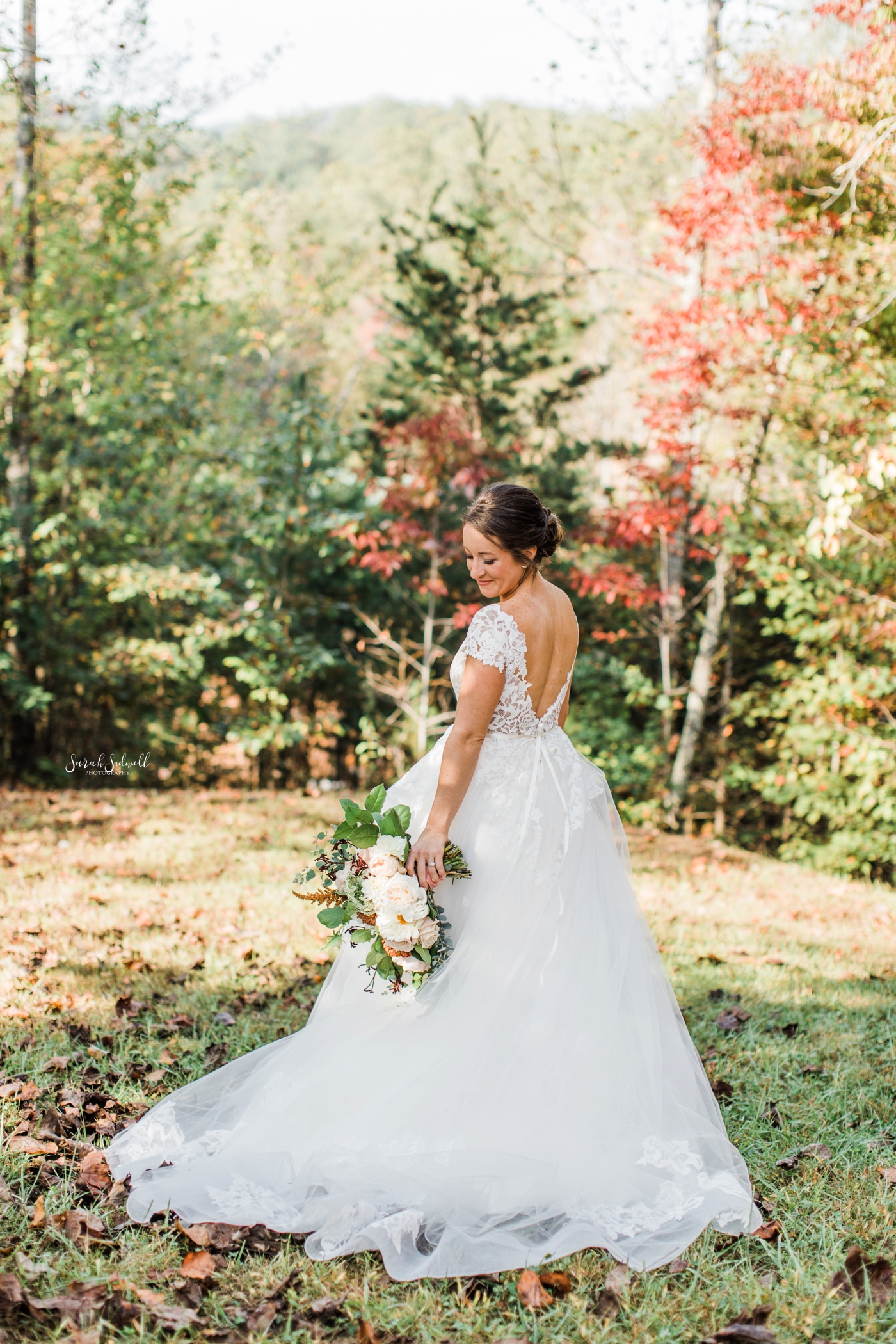A bride wearing a white dress stands among wild flowers. 