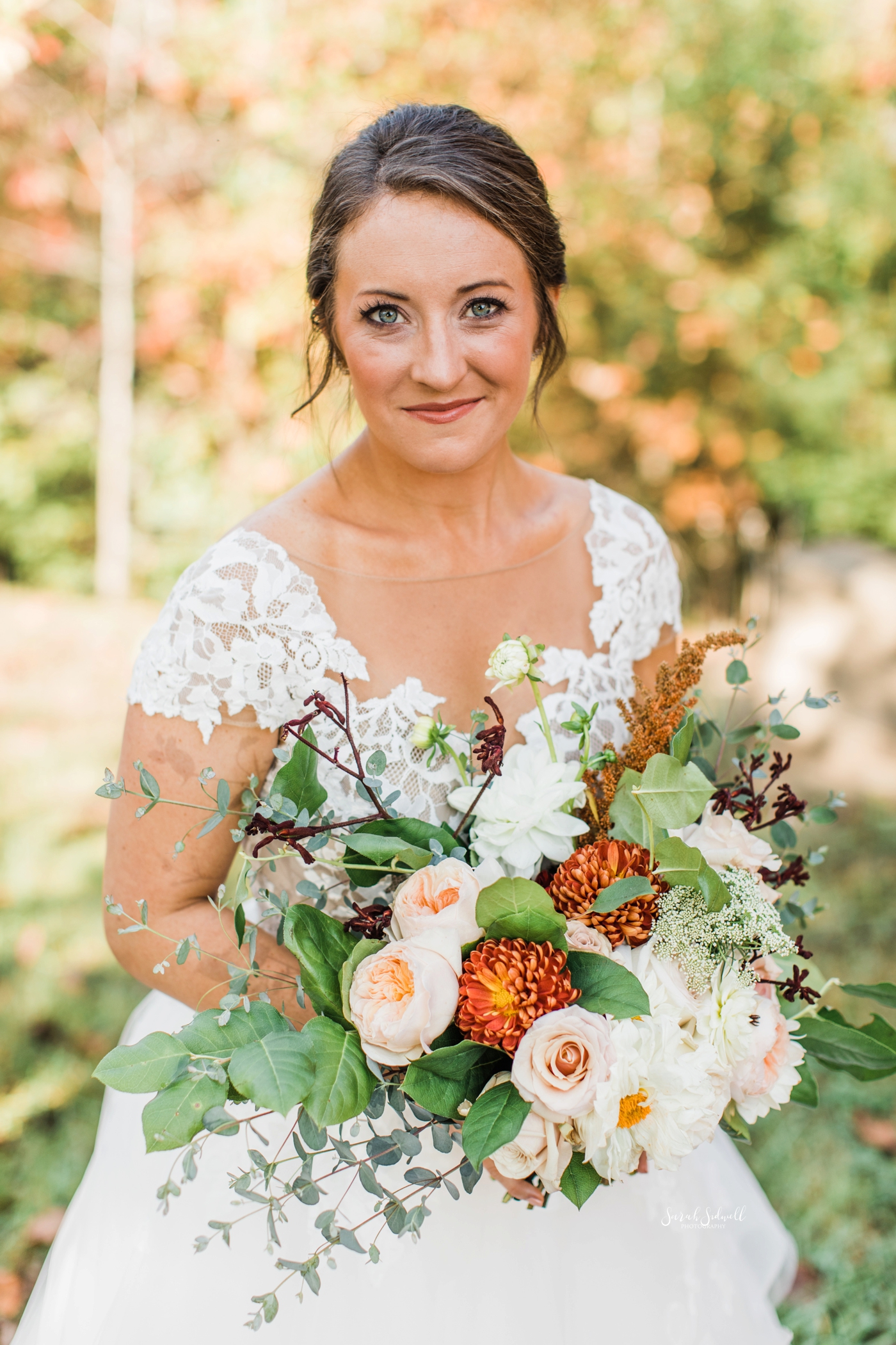 A bride holds her bouquet and smiles at the camera. 