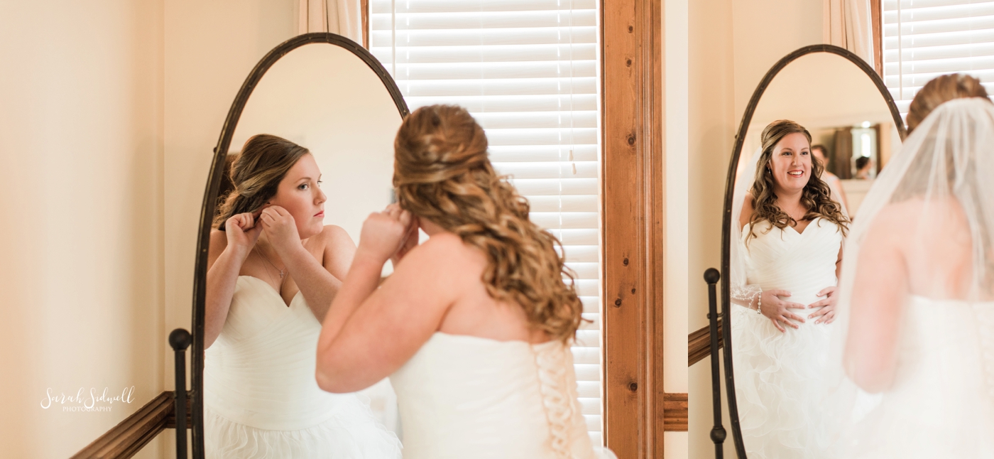 A bride puts her earrings into her ears. 