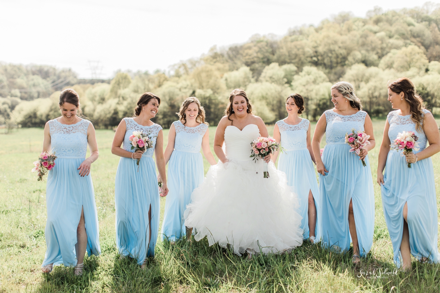 A bride laughs with her bridal party. 