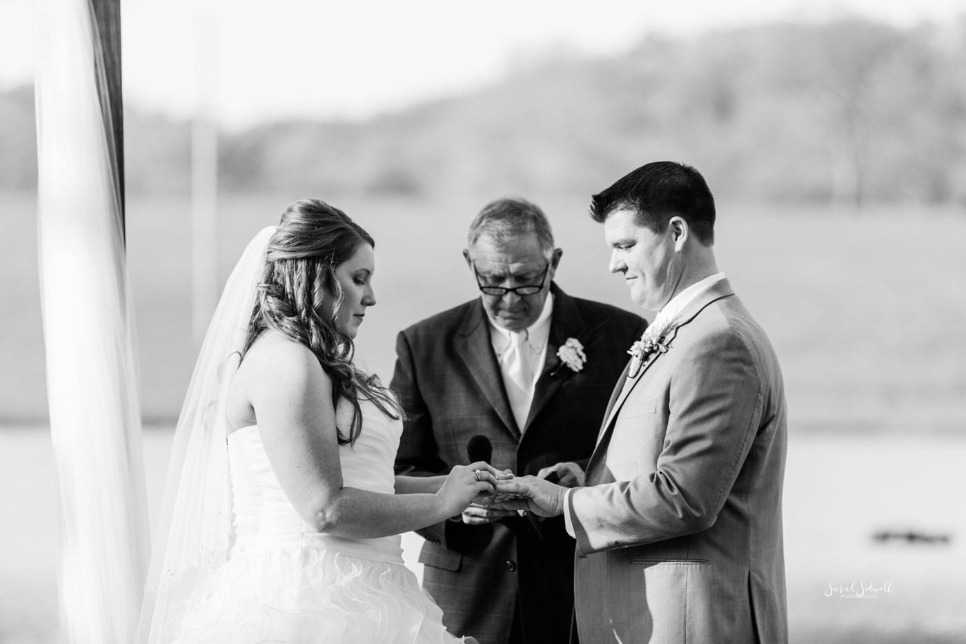 A bride and groom say their vows while holding hands. 