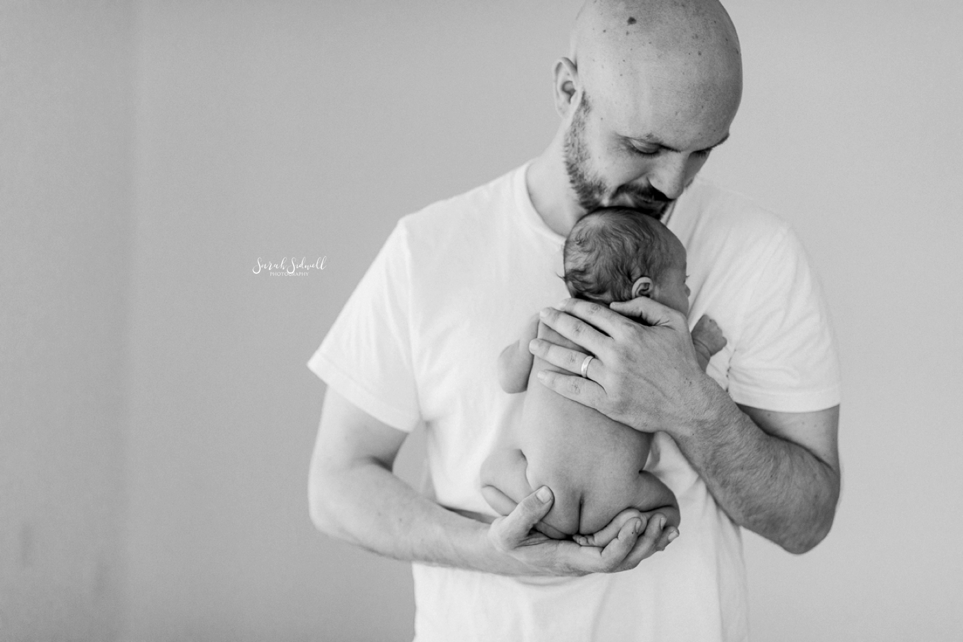 A man holds his newborn baby close to his chest. 