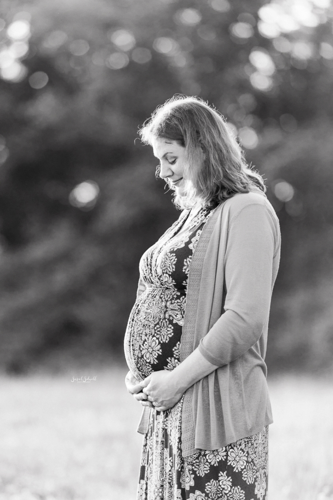 A woman holds her belly during her family maternity photography session. 