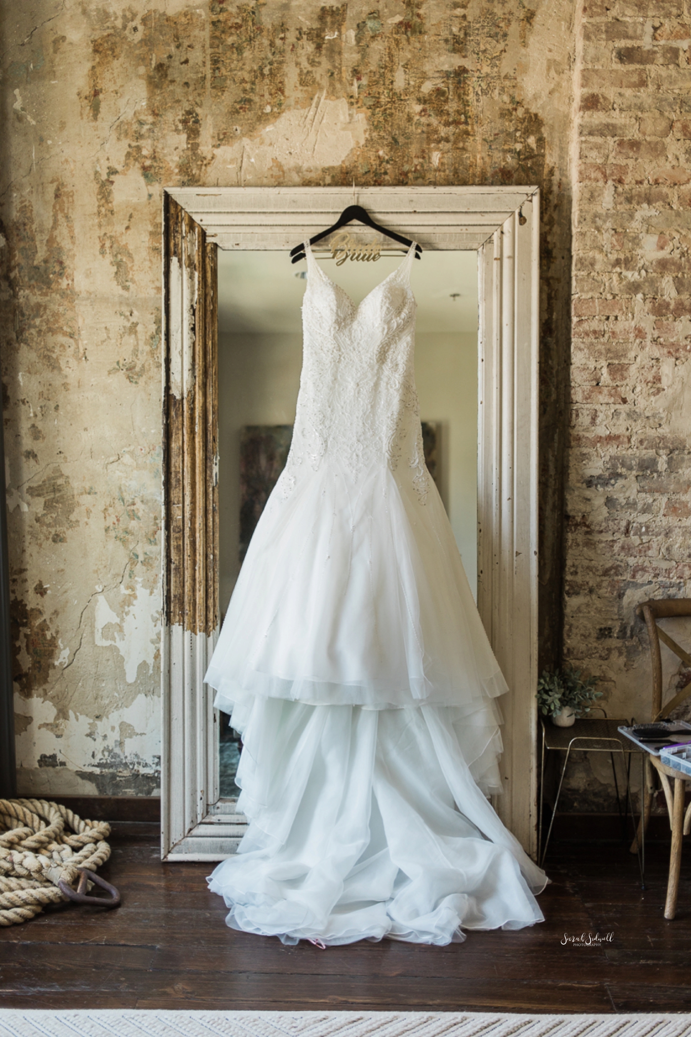 A wedding dress is hanging in a doorway of a venue. 