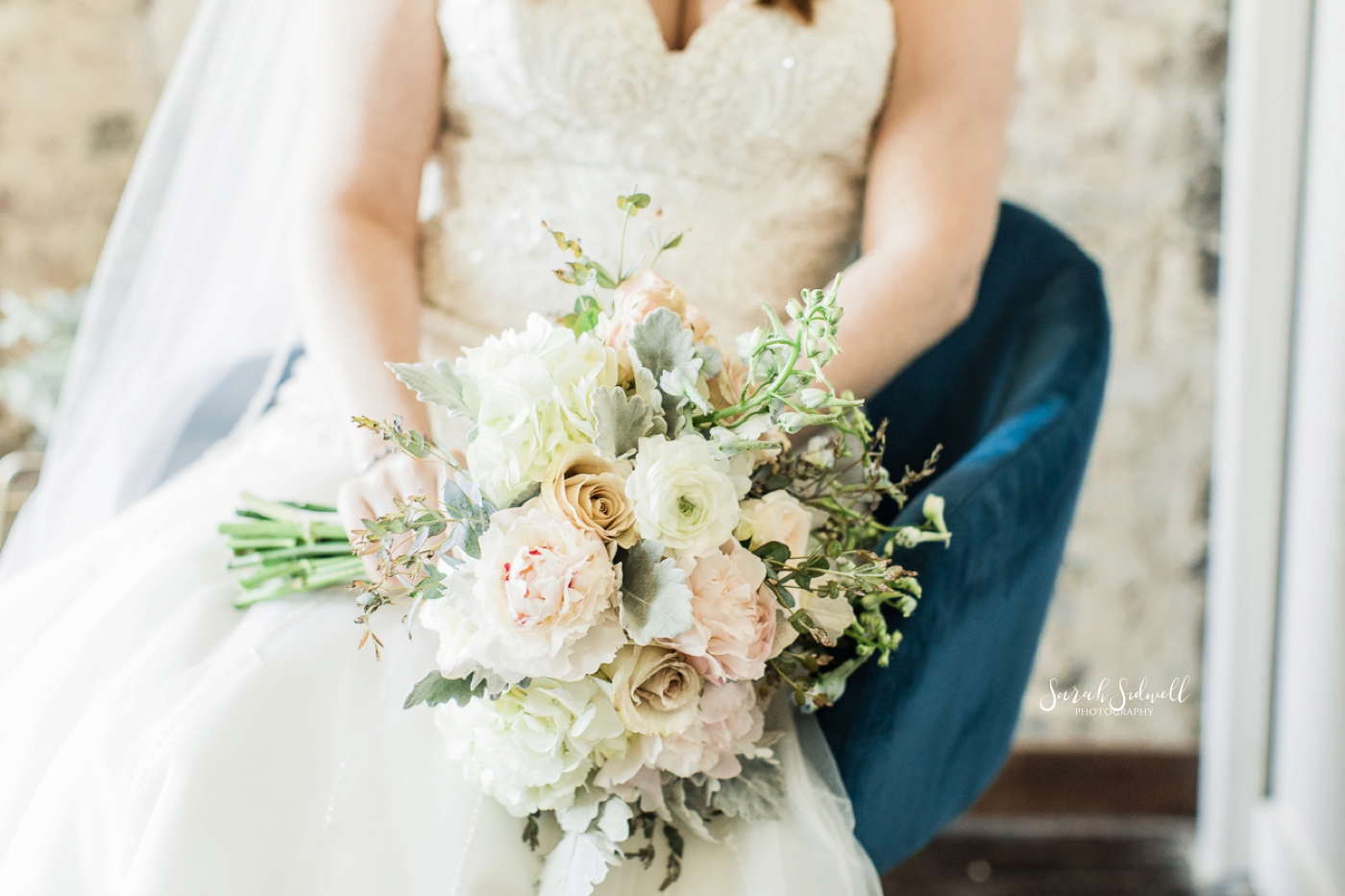 A bride holds her bouquet in her lap. 