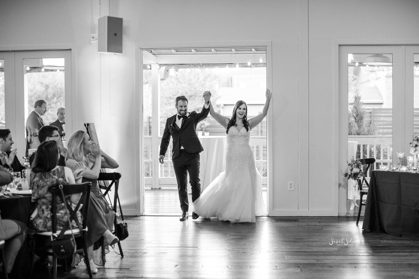 A bride and groom celebrate as they walk into their venue. 