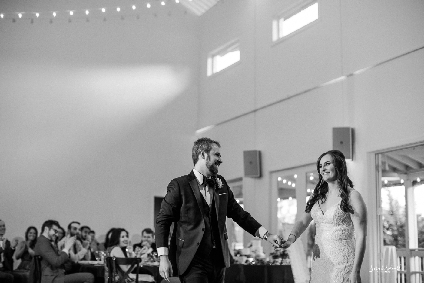 A man leads his new wife onto the dance floor for their first dance. 