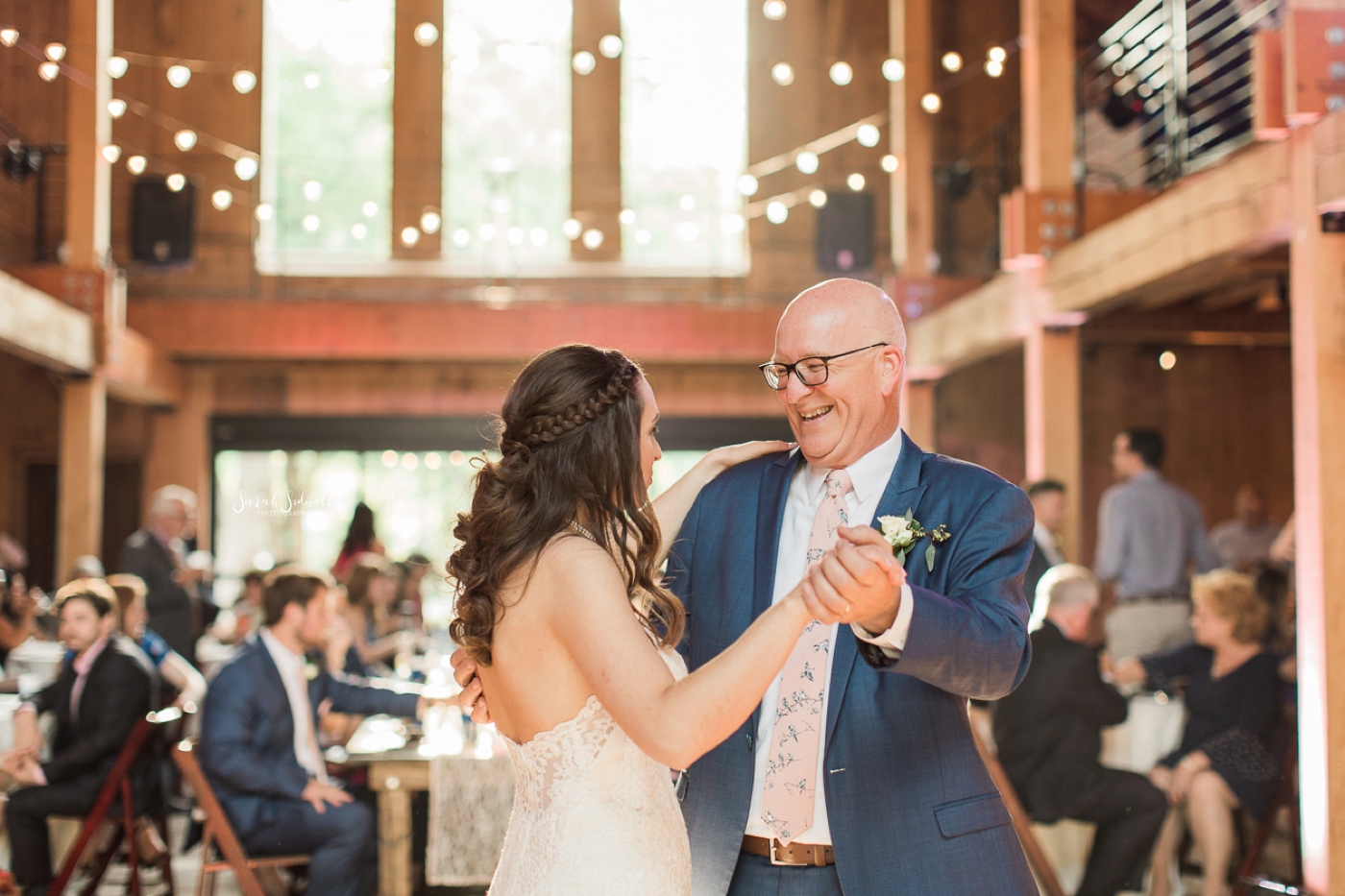 A man dances with his daughter at her wedding. 