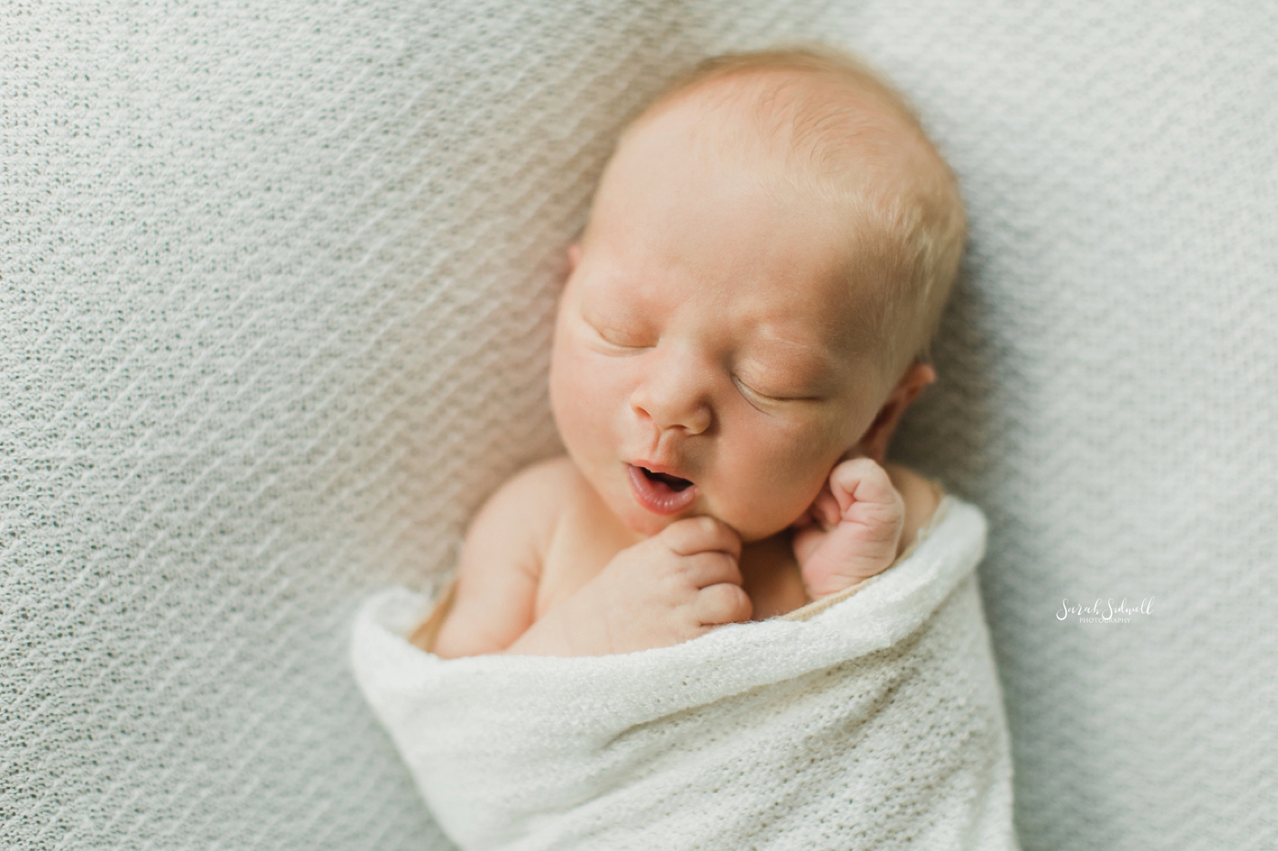 A baby yawns for his newborn family photos. 
