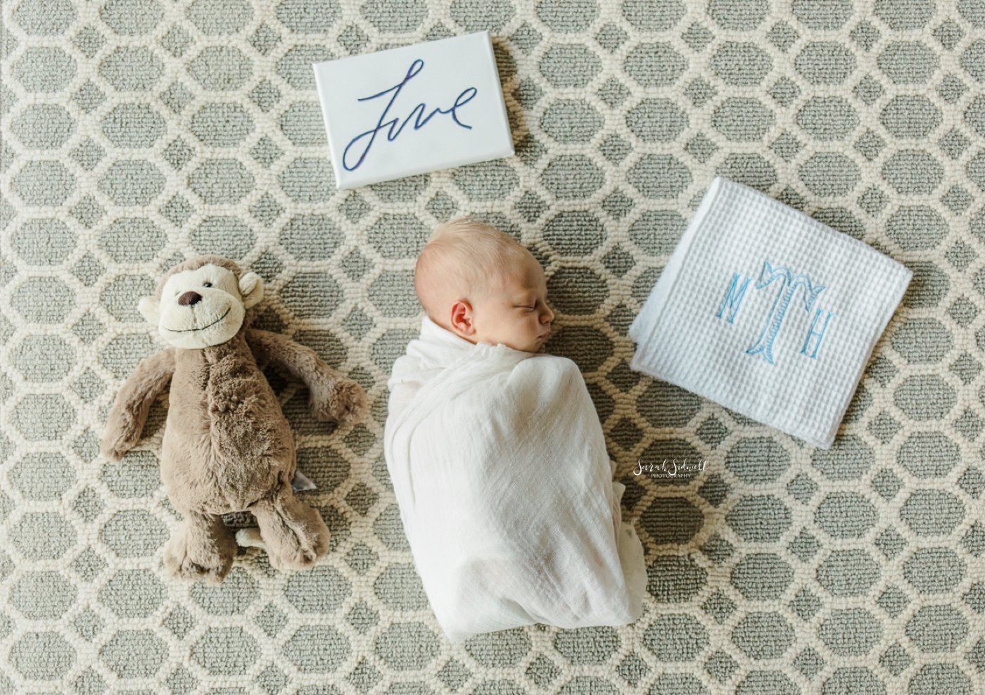 A baby sleeps next to some of his newborn toys. 
