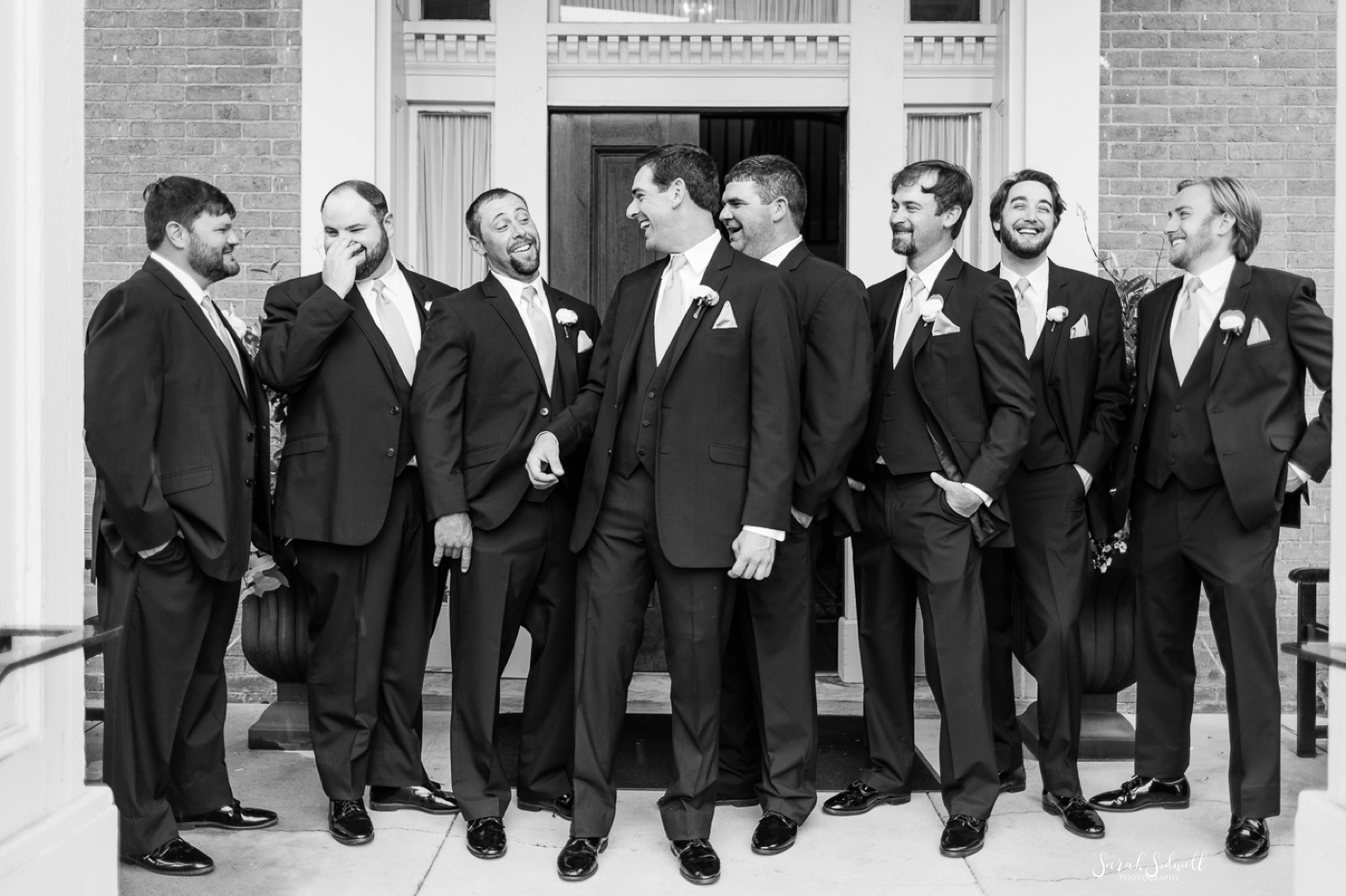 A groom laughs with his groomsmen before the wedding. 