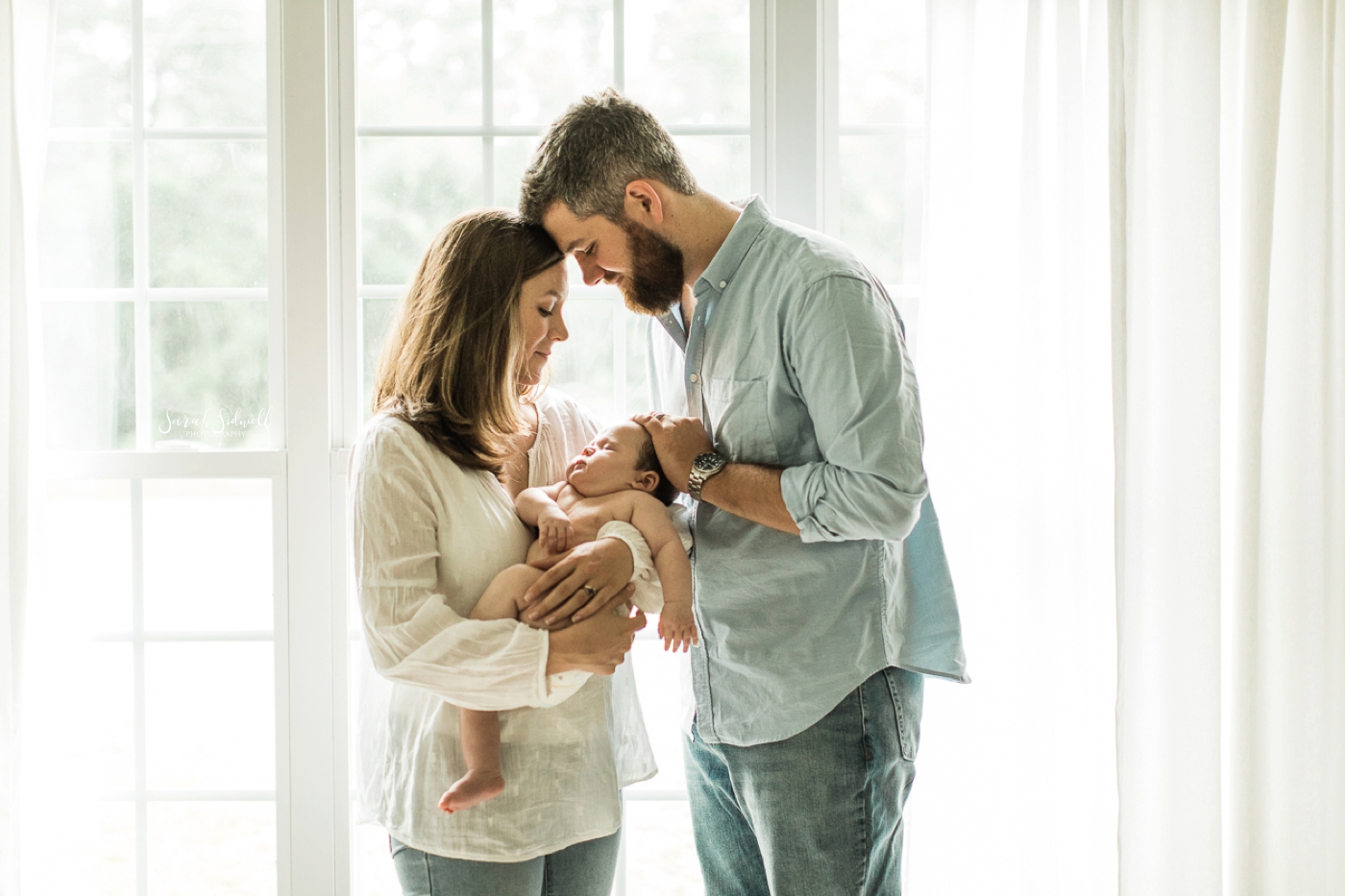 A couple look over their baby during a three month baby session. 