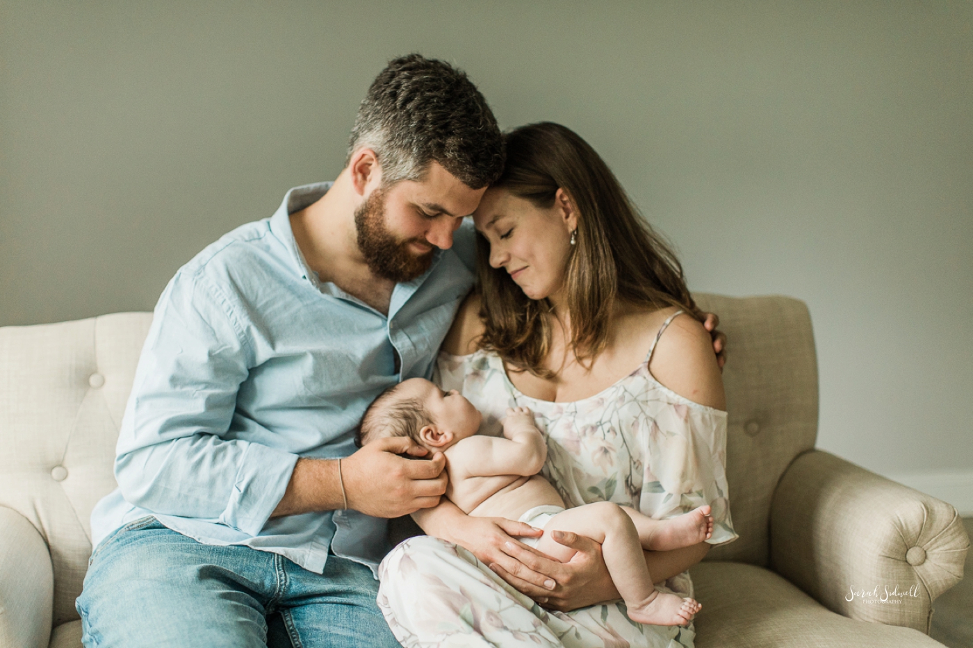 A couple snuggle their baby during a three month baby session. 