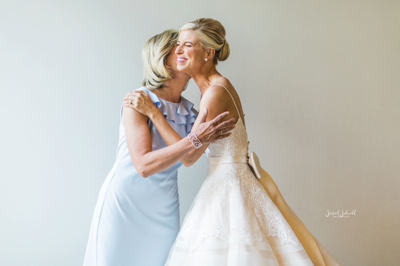 A mother kisses her daughter on the cheek before her wedding. 