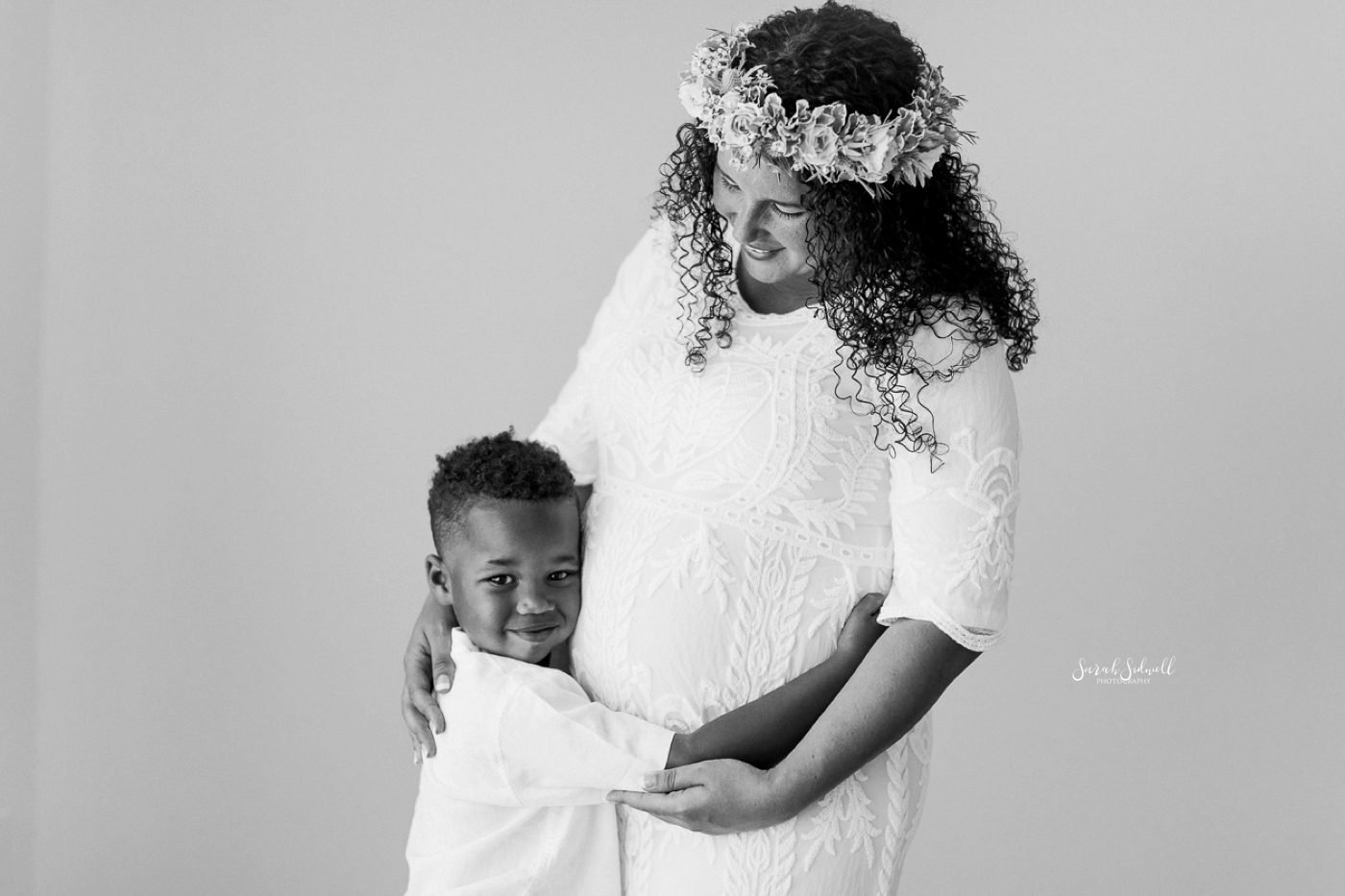 During a family maternity session, a boy hugs his mom. 