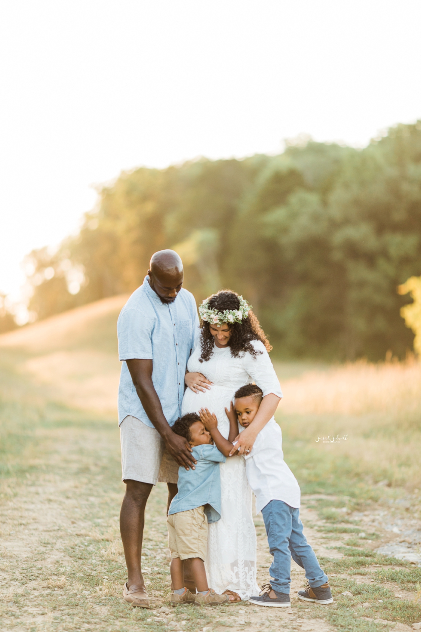 Two parents hug their sons during a family maternity session. 
