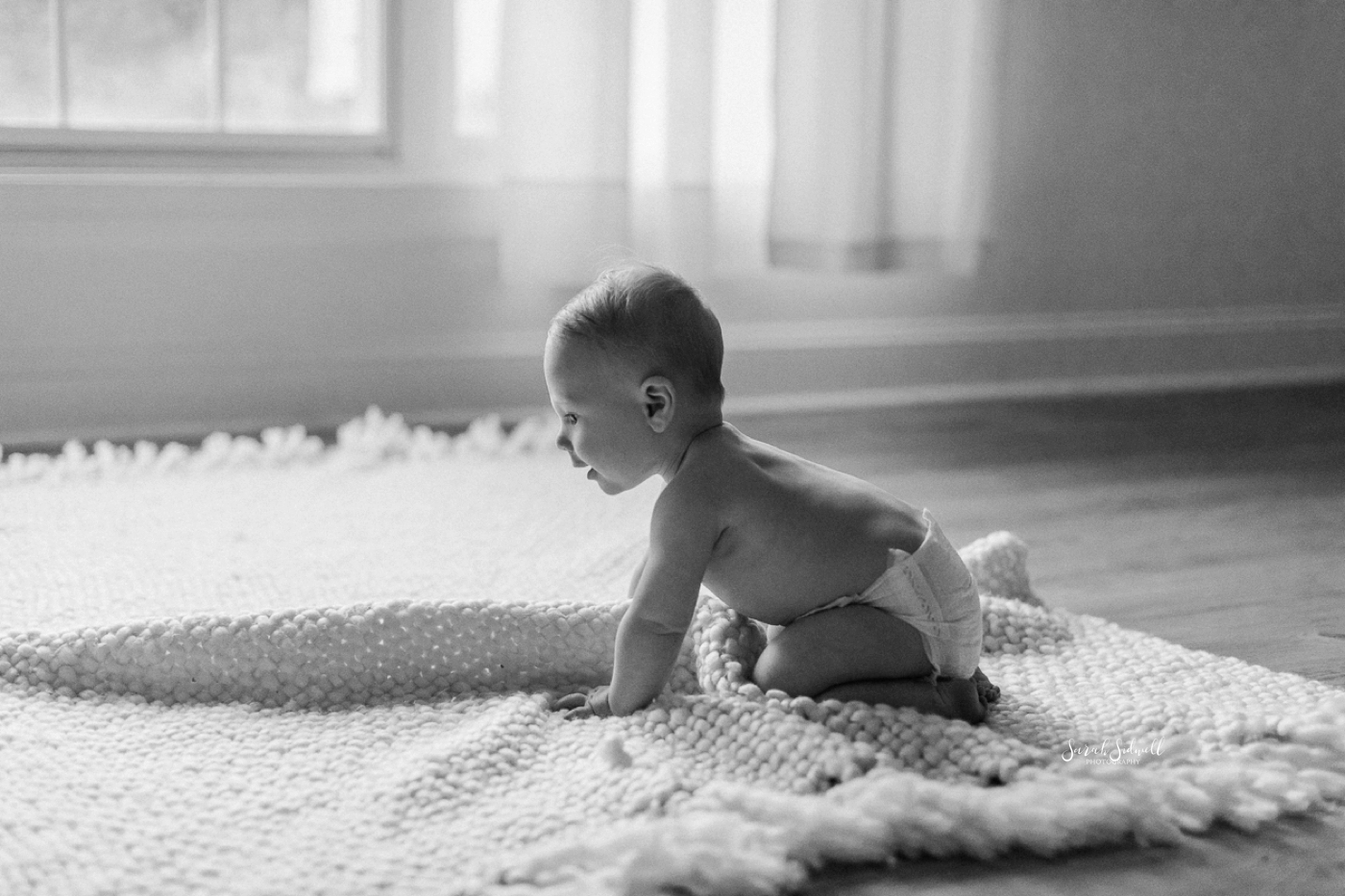 A baby crawls on a blanket. 