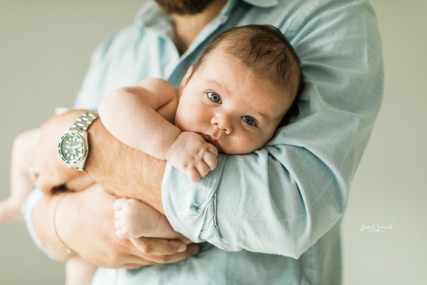 A dad rocks his baby in his arms. 