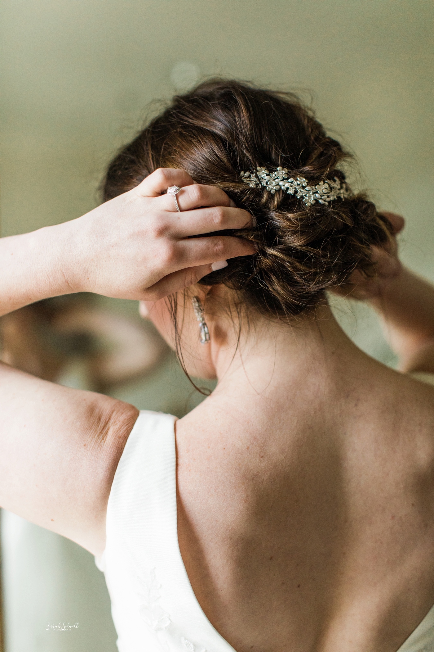 A bride pins some flowers into her hair. 