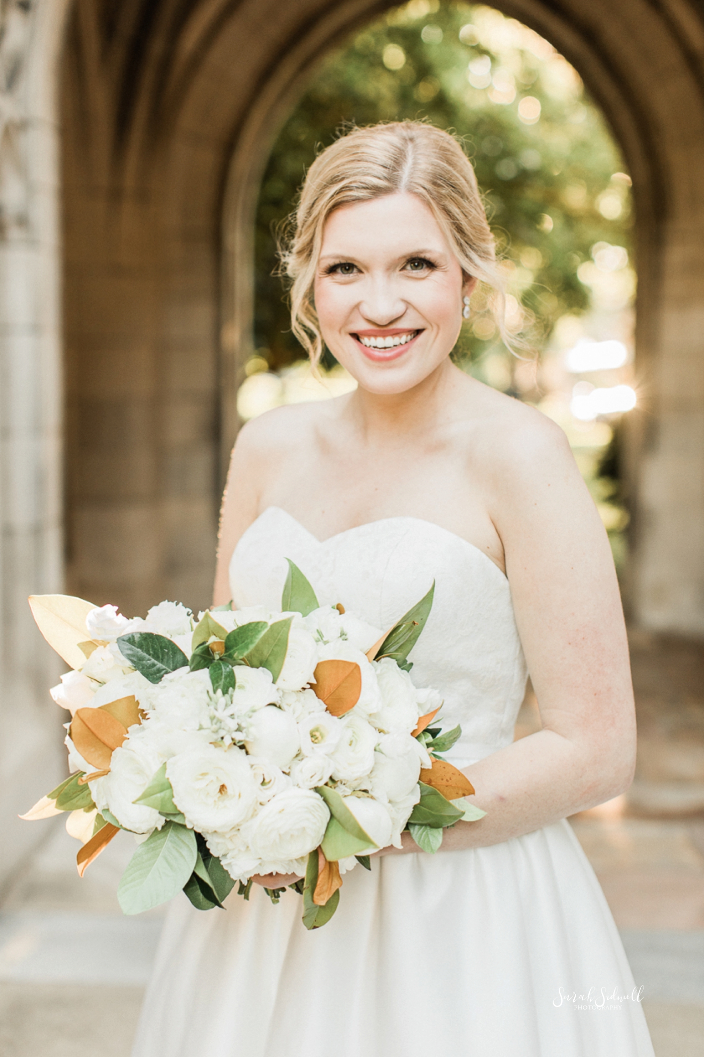 A bride holds her bouquet and smiles. 