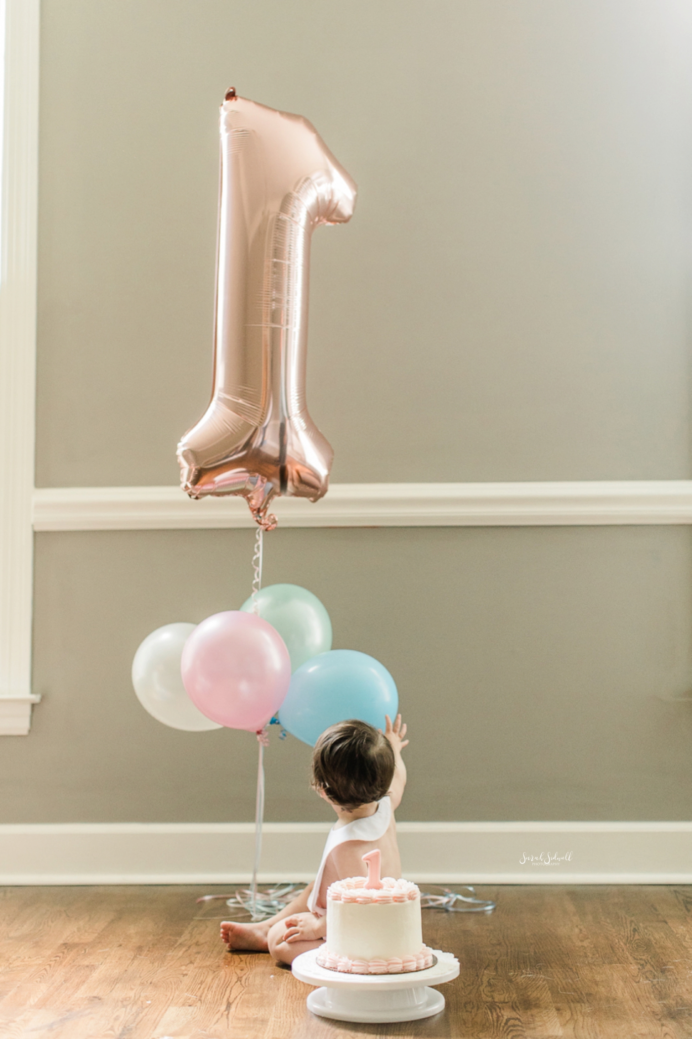A baby girl plays with her first birthday balloons. 